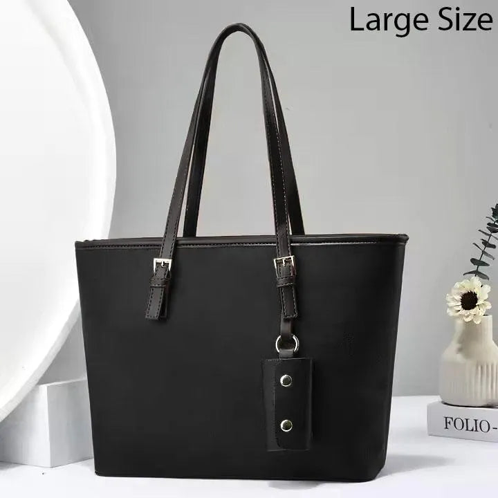 Black handbag with a strap on a light gray background