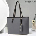 Gray handbag with black straps on a light gray background