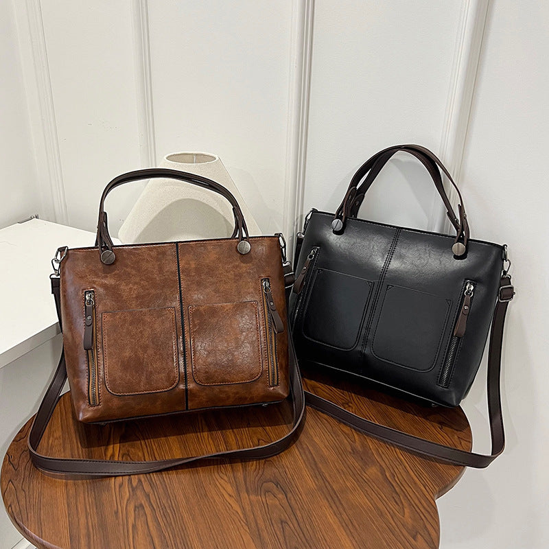 Brown and black leather handbags on a wooden surface with a white background