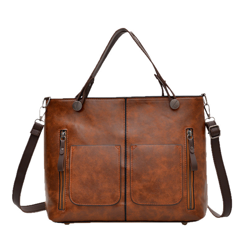 Brown leather handbag with shoulder strap on a white background