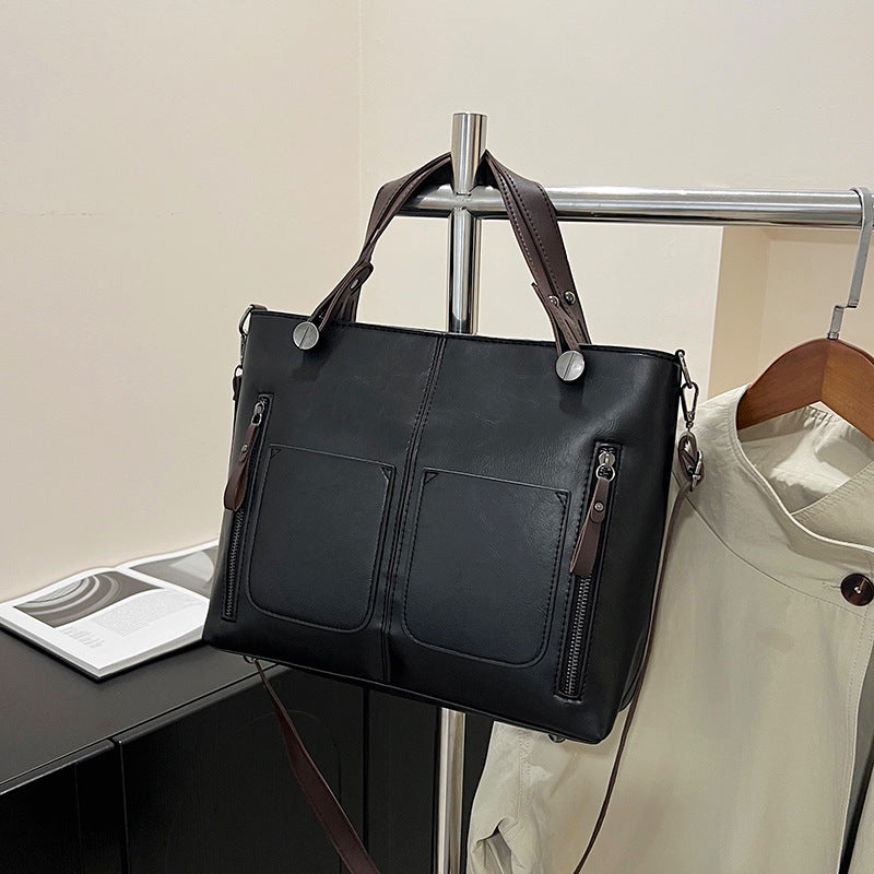 Black leather handbag hanging on a rack with a neutral background